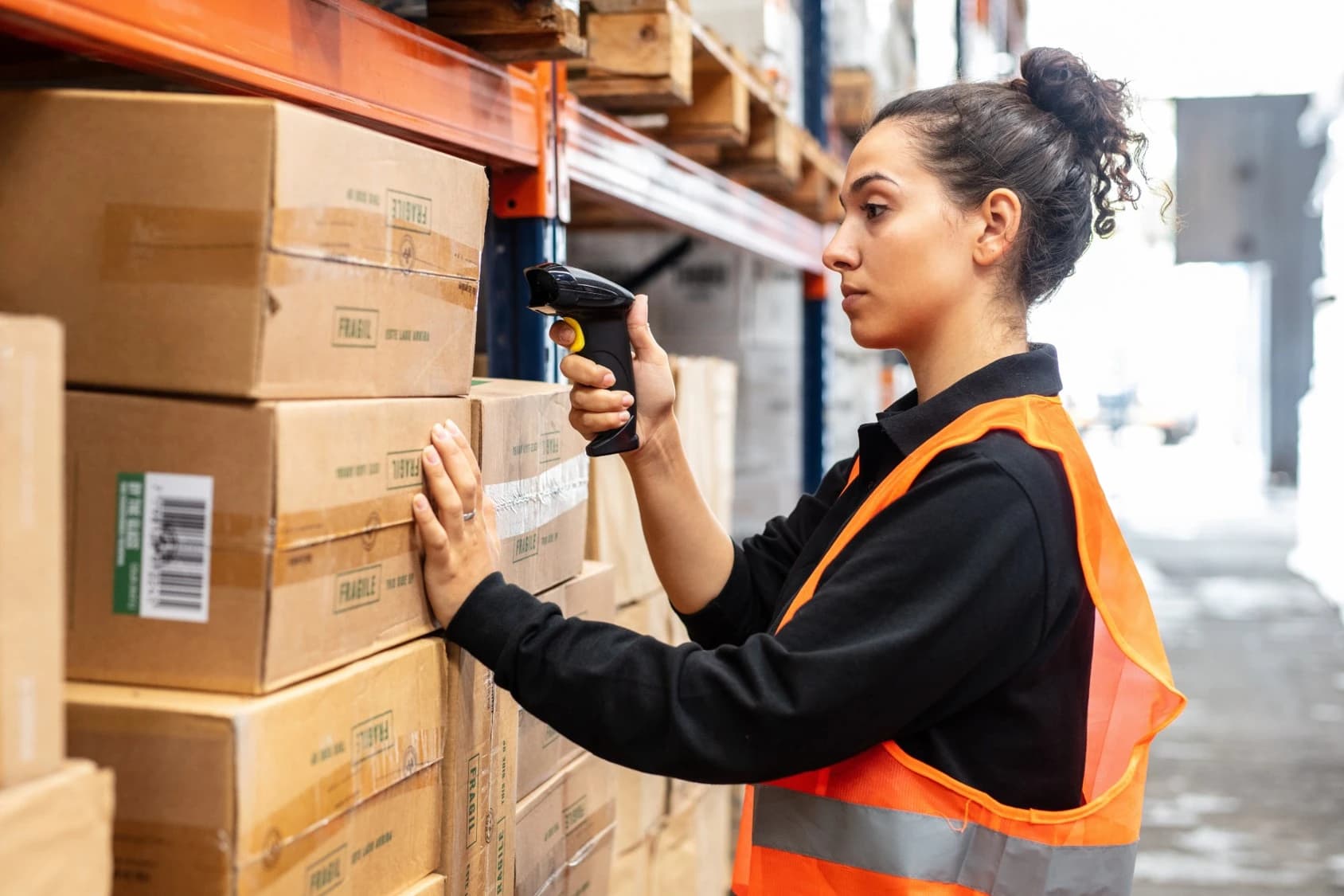 Opératrice scannant des colis en entrepôt avec une douchette connectée
